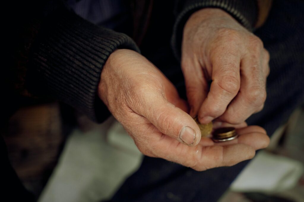 The hands of an elderly man consider small things. Concept of poverty and low pensions.